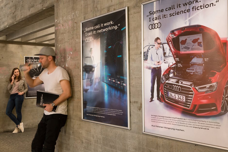 Ein paar Leute die an einer Mauer vor Edgar Campus Werbeplakaten stehen