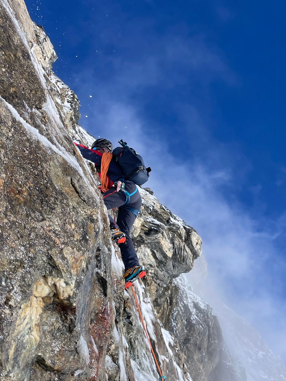 Bergführer beim Aufstieg in der steilen Felswand auf dem Weg zum Gipfel, gesichert mit einem Seil