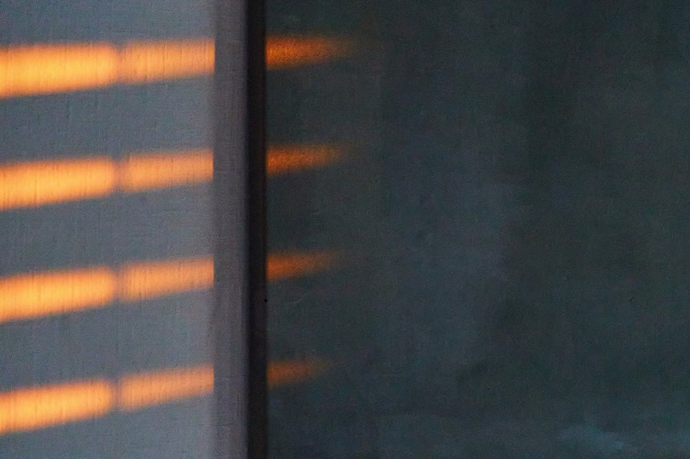 The image shows the photograph of streaks of sunlight falling onto a dark abstract painting.